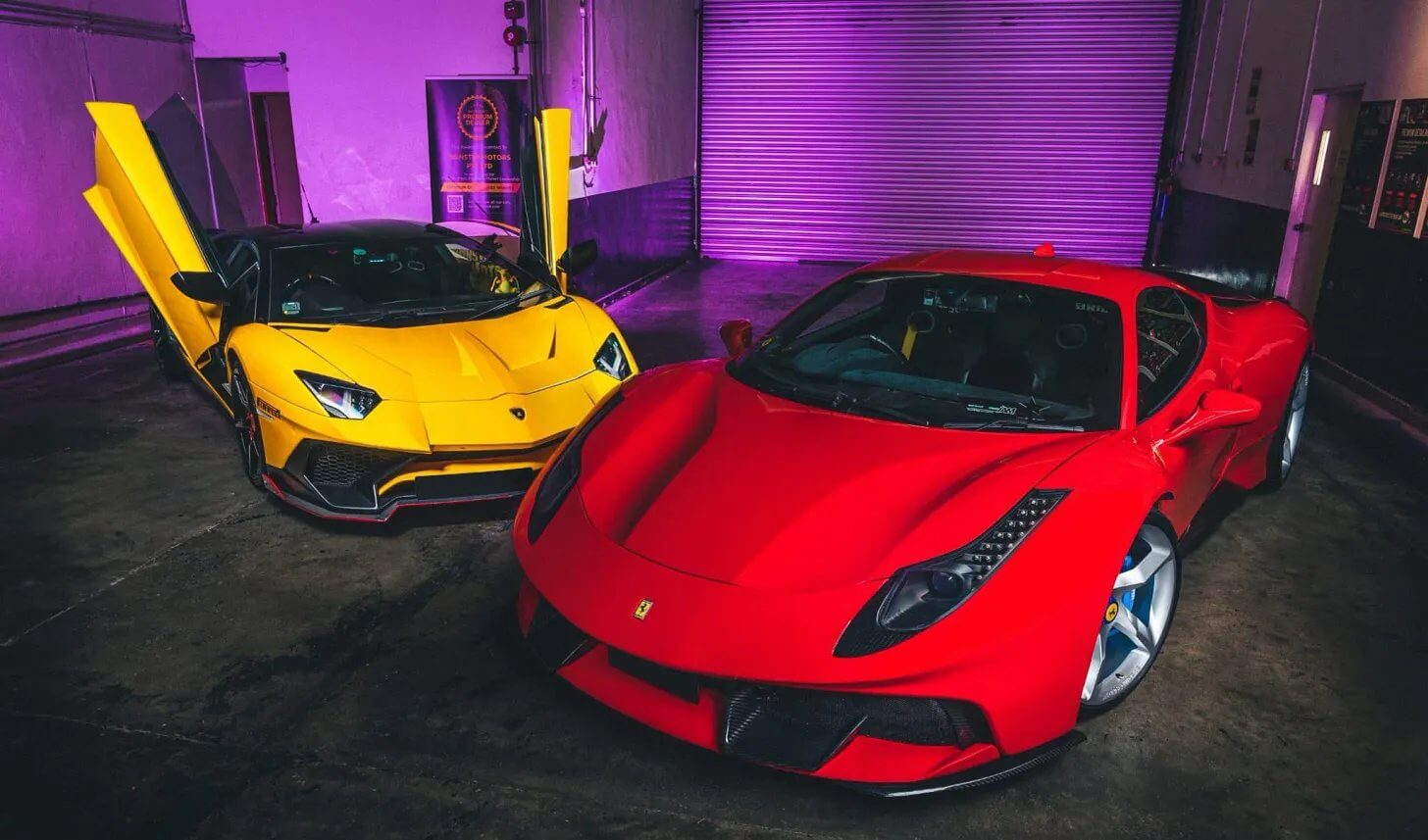 Ferrari vermelha e Lamborghini amarela em garagem com luz roxa